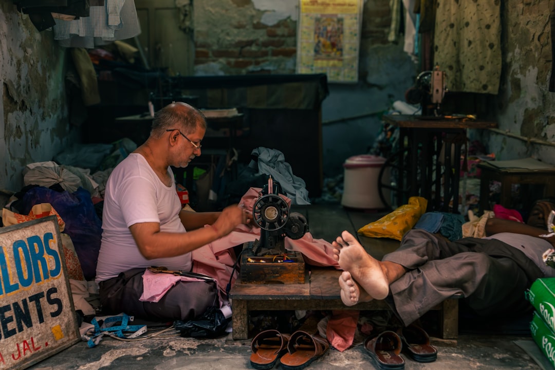 An old tailor sewing clothes in his small, cluttered workshop