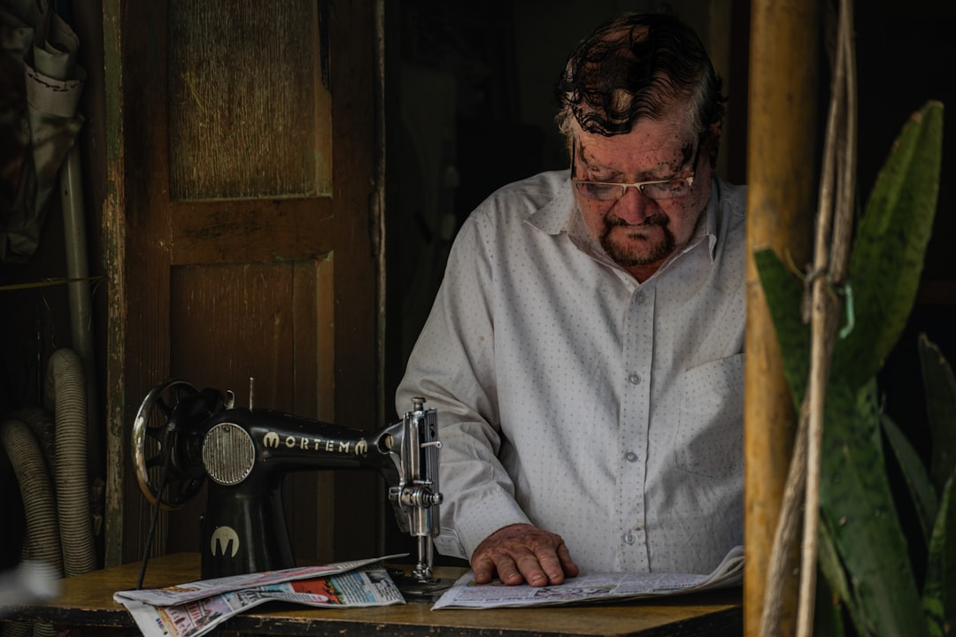 Man in white shirt sewing with vintage machine